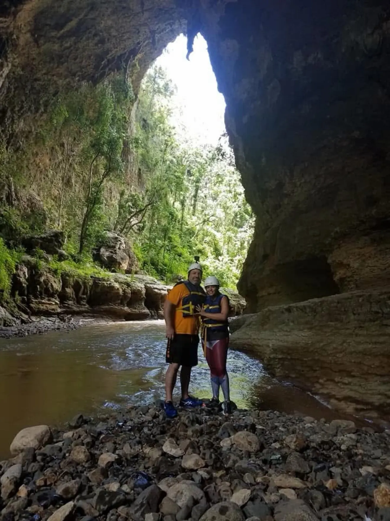 Two visitors in helmets and life vests inside a rocky river canyon