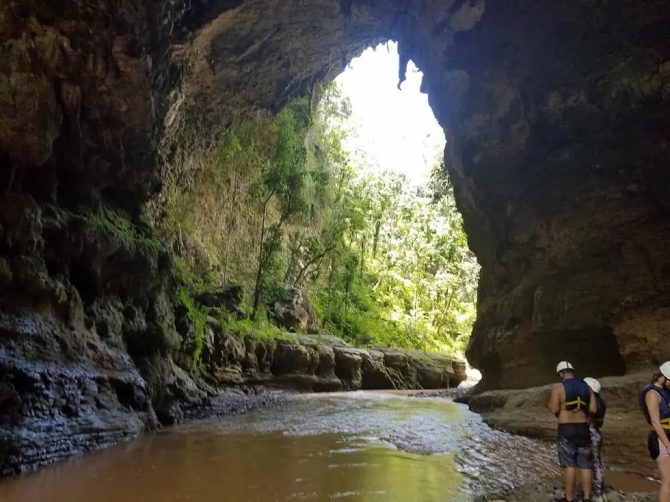 Visitors exploring a shallow river through a large cave