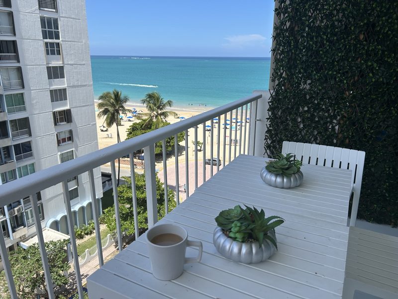 Morning coffee on the Terra Noir balcony table with Isla Verde Beach and the ocean beyond the railing